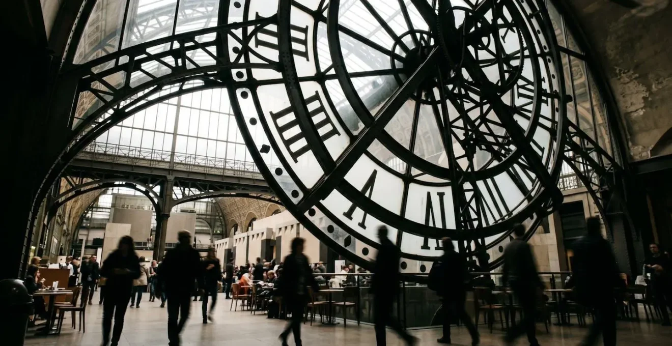Vue en contre-plongée de l'horloge monumentale depuis le Café Campana avec des visiteurs en silhouette